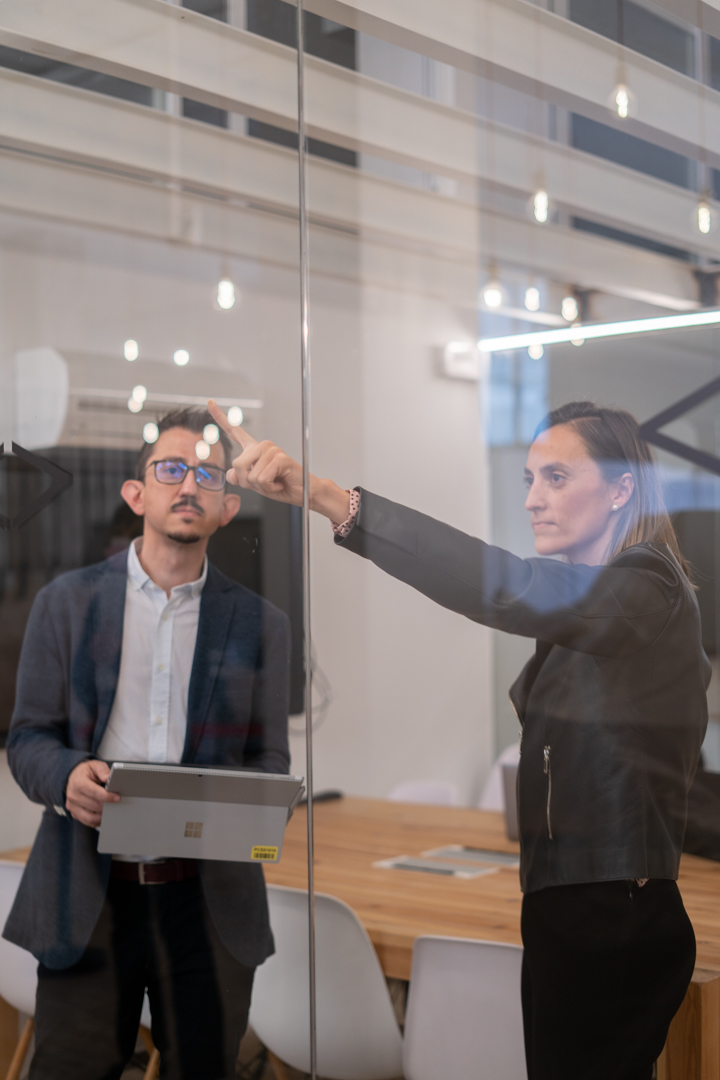 Profesionales trabajando juntos ante una pizarra de cristal
